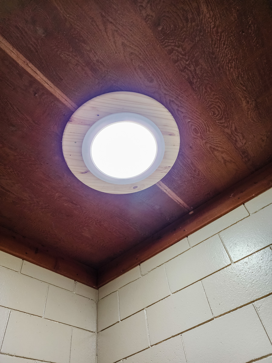 a bathroom with a toilet and a round window - Bald Eagle Lake Park Daylighting Project