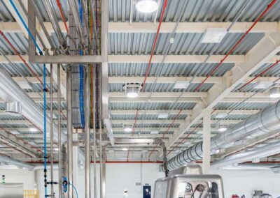 a large industrial building with pipes and lights - commercial grade skylights